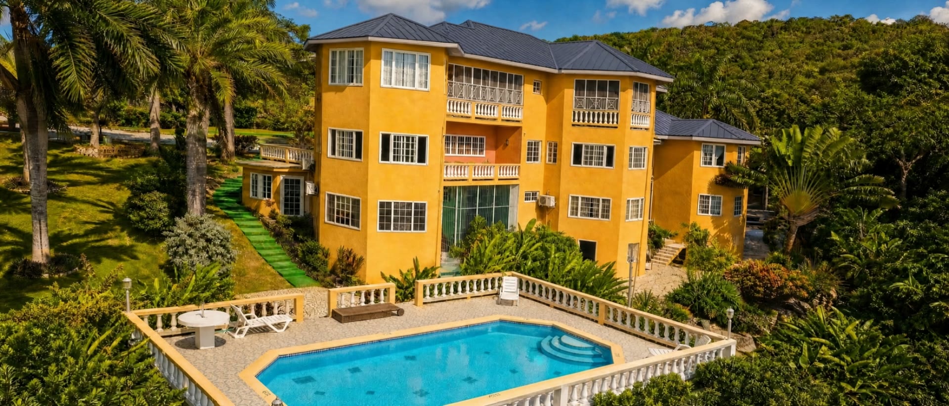 Emerald View Villa from the air — three storeys of mustard-yellow stucco above the swimming pool